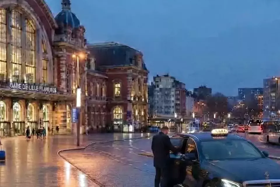 Taxi Lille Angres : taxi noir stationné devant une gare en soirée