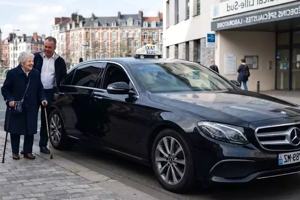 Taxi Lille Aniche : chauffeur de taxi aidant une passagère devant un centre médical