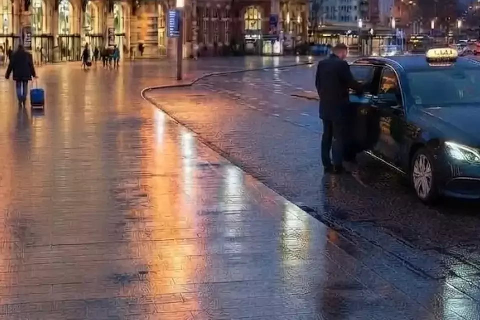 Taxi Lille Annœullin : chauffeur ouvrant la portière d’un taxi devant une gare