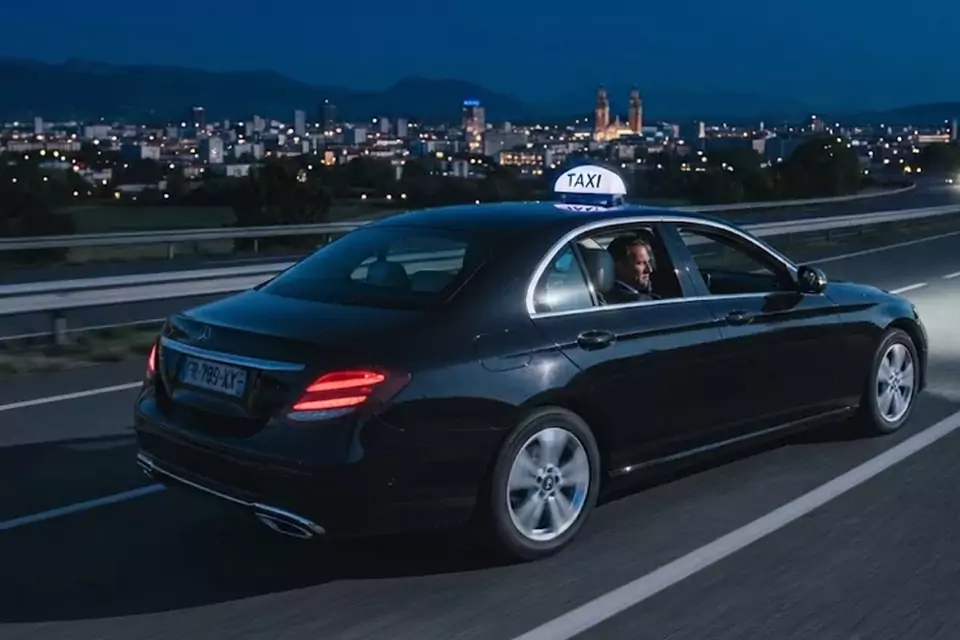 Taxi Lille Aulnoye-Aymeries : taxi noir en trajet de nuit avec la ville en arrière-plan