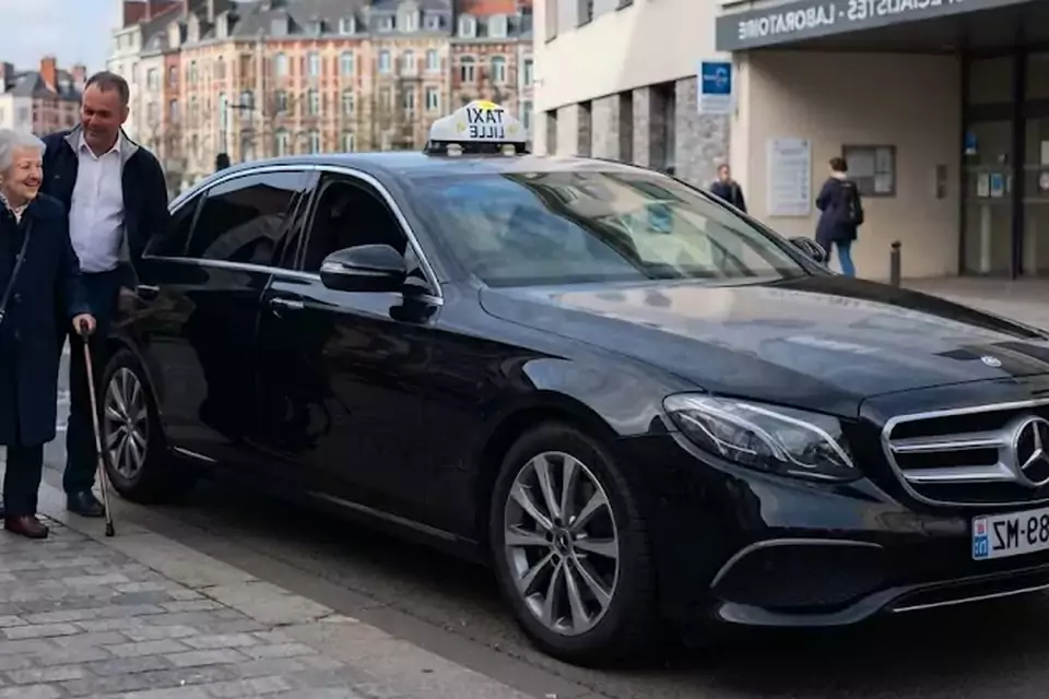 Taxi Lille Avesnes-le-Comte : chauffeur de taxi aidant une passagère devant un centre médical