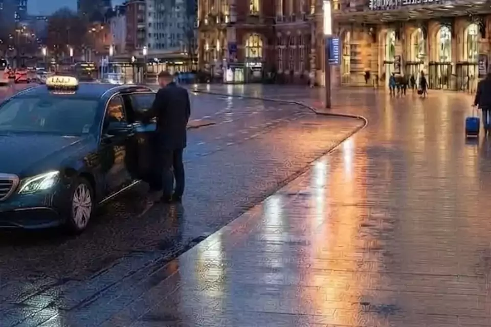 Taxi Lille Cassel : chauffeur ouvrant la portière d’un taxi devant une gare