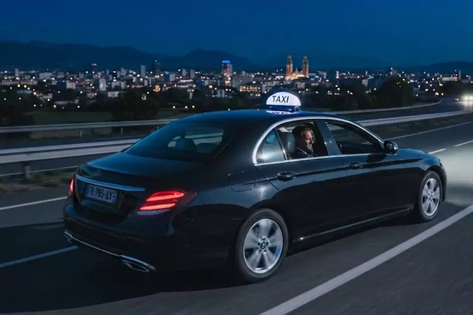 Taxi Lille Coudekerque-Branche : taxi noir en trajet de nuit avec la ville en arrière-plan