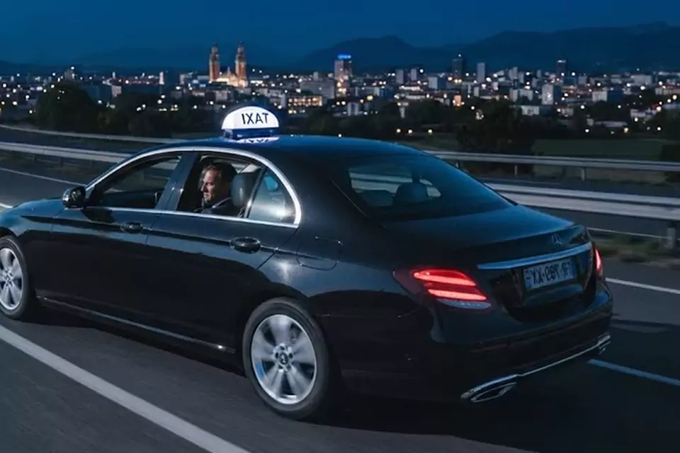 Taxi Lille Feignies : taxi noir en trajet de nuit avec la ville en arrière-plan
