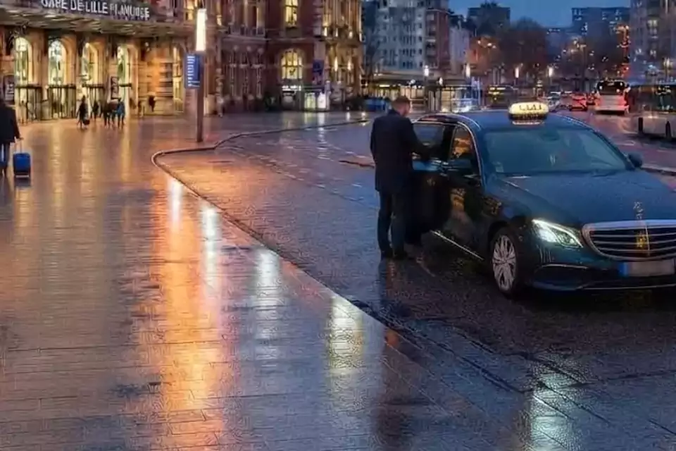 Taxi Lille Fort-Mardyck : chauffeur ouvrant la portière d’un taxi devant une gare