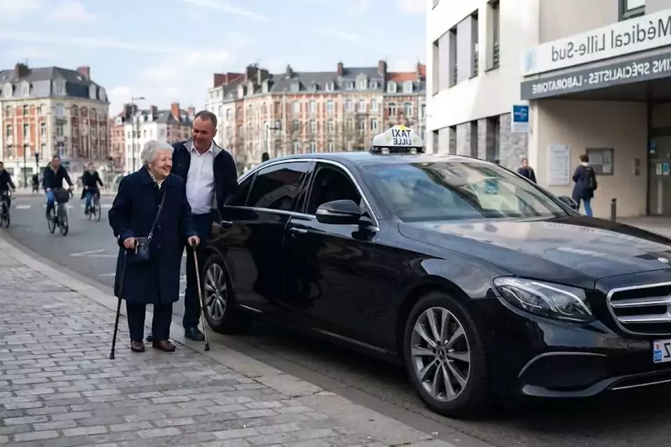 Taxi Lille Fruges : chauffeur de taxi aidant une passagère devant un centre médical