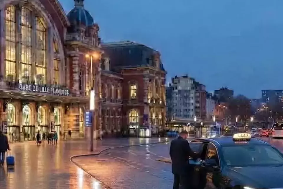 Taxi Lille Haisnes : taxi noir stationné devant une gare en soirée