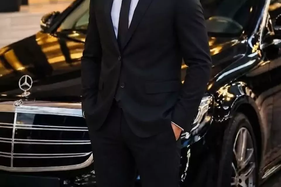 Taxi Lille Harnes : chauffeur de taxi souriant devant sa berline noire