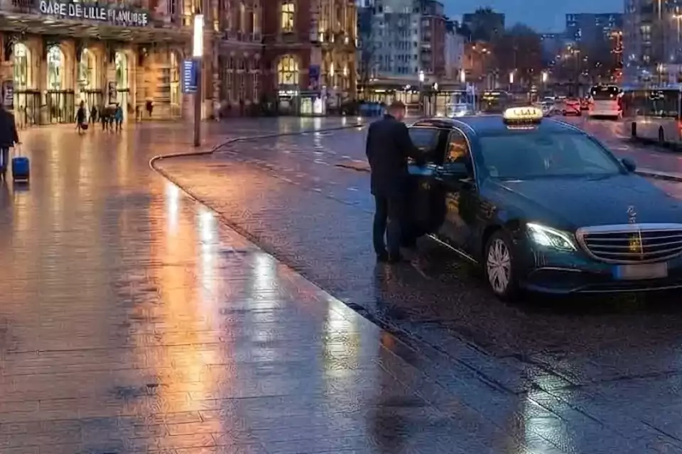 Taxi Lille Hénin-Beaumont : chauffeur ouvrant la portière d’un taxi devant une gare