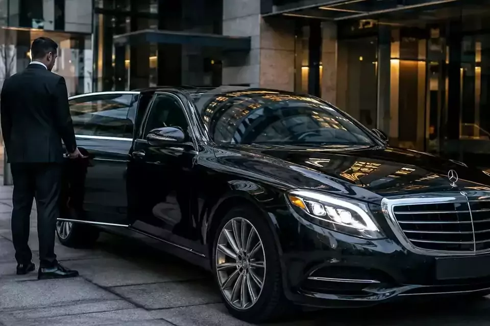Taxi Lille Isbergues : chauffeur ouvrant la portière d’une berline noire devant un hôtel