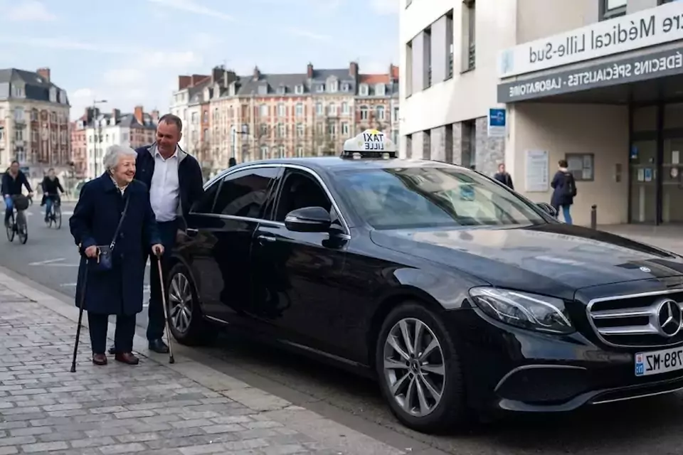 Taxi Lille Labeuvrière : chauffeur de taxi aidant une passagère devant un centre médical
