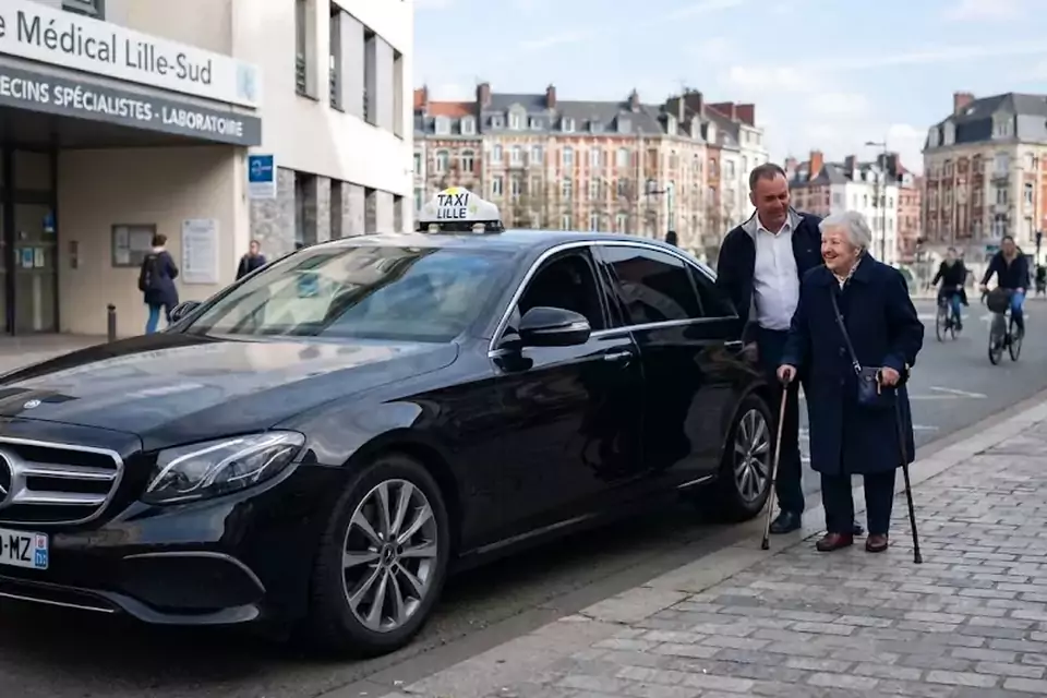 Taxi Lille Landrecies : chauffeur de taxi aidant une passagère devant un centre médical