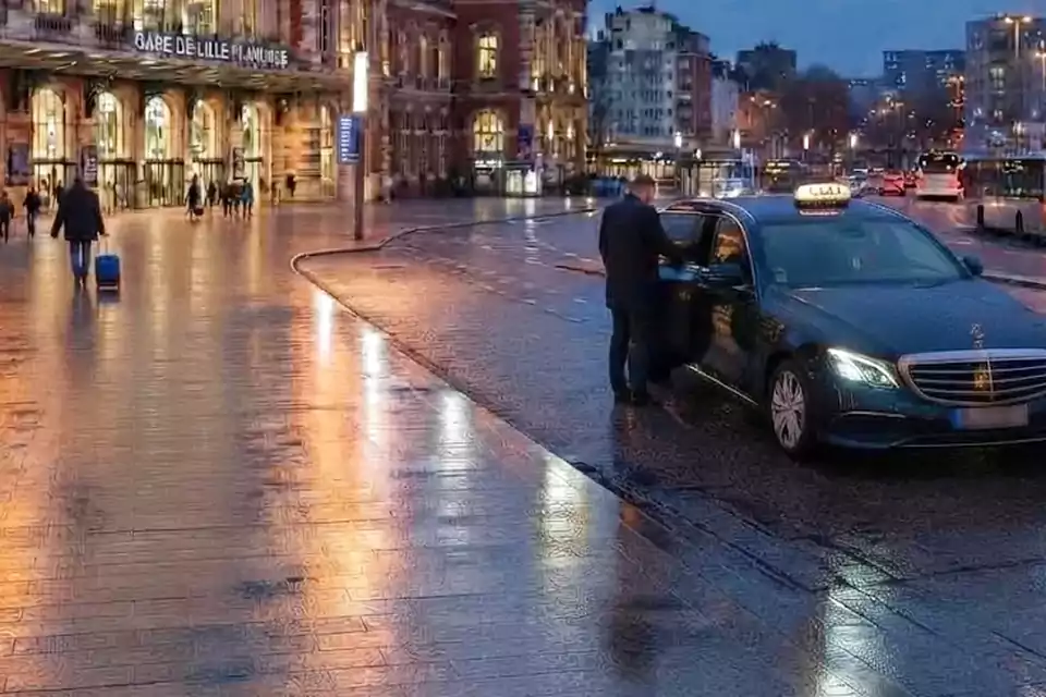Taxi Lille Le Cateau-Cambrésis : chauffeur ouvrant la portière d’un taxi devant une gare