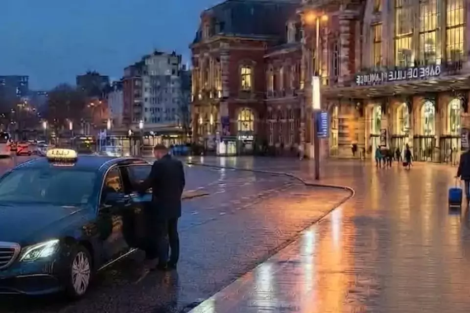 Taxi Lille Liévin : taxi noir stationné devant une gare en soirée