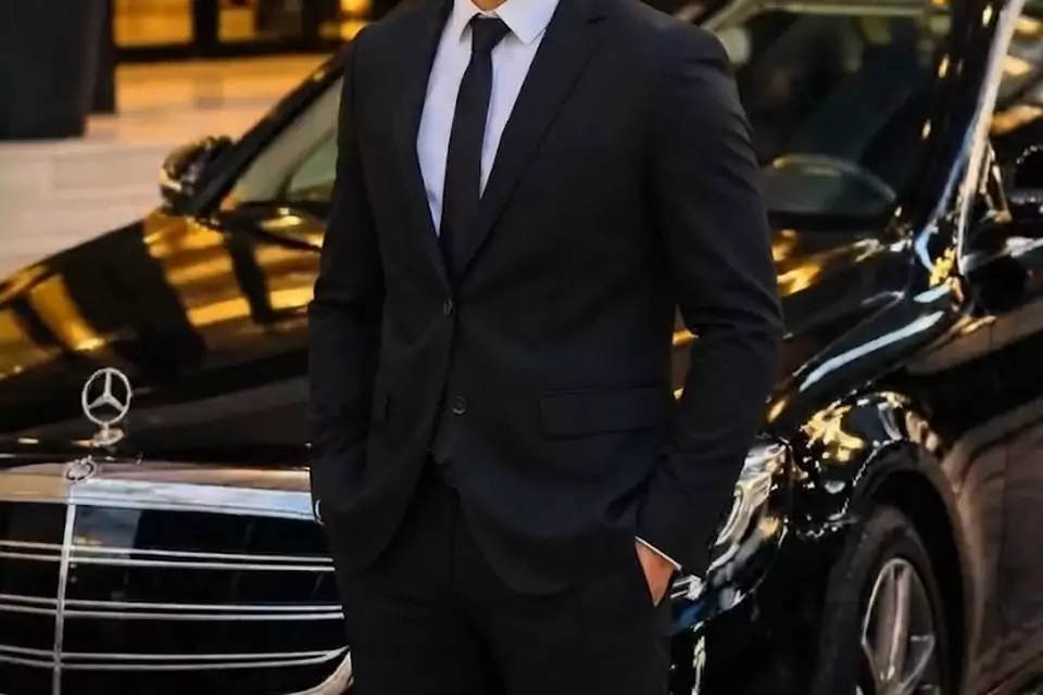 Taxi Lille Longuenesse : chauffeur de taxi souriant devant sa berline noire