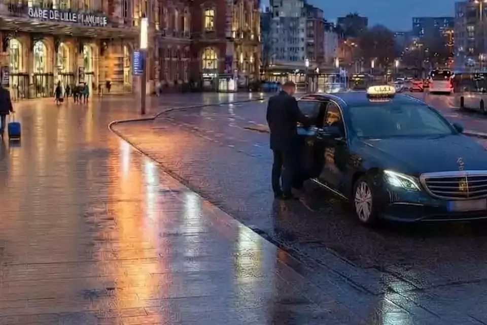 Taxi Lille Louvroil : taxi noir stationné devant une gare en soirée