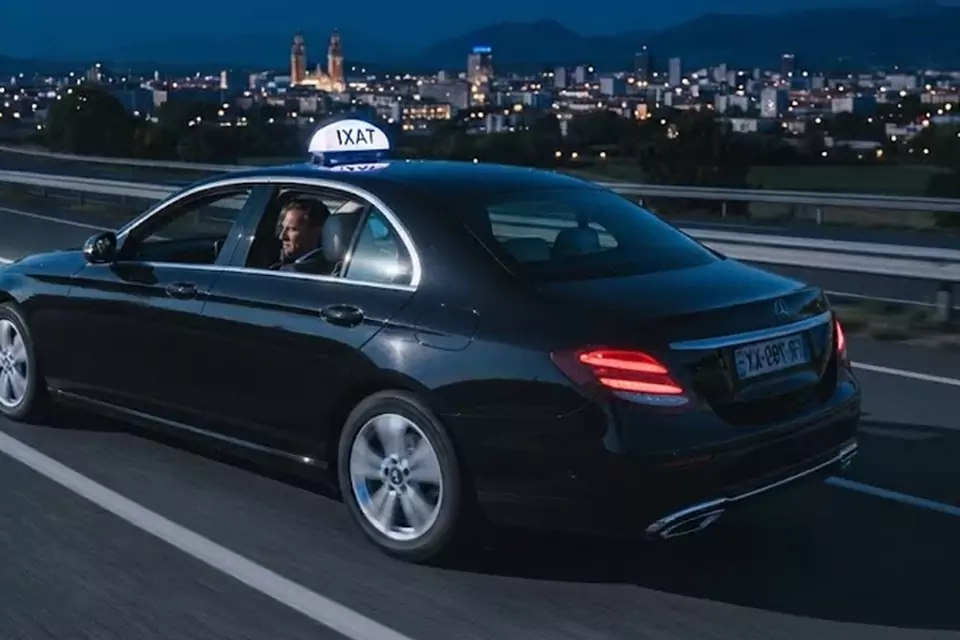 Taxi Lille Mons : taxi noir en trajet de nuit avec la ville en arrière-plan