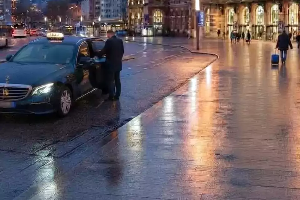 Taxi Lille Port de Calais : taxi noir stationné devant une gare en soirée