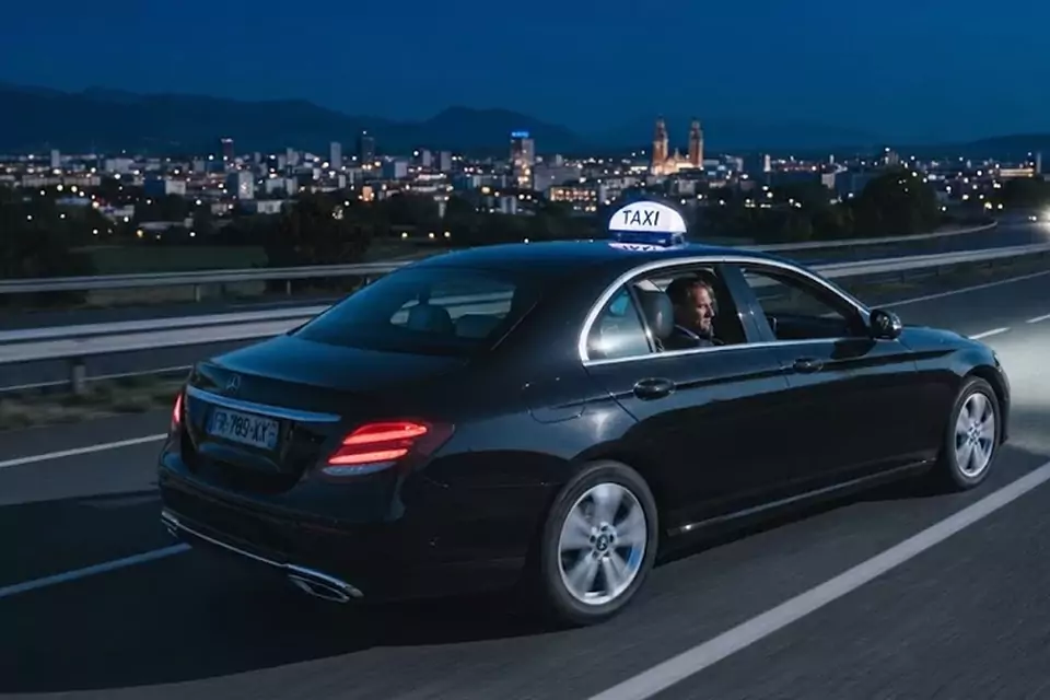 Taxi Lille Seclin : taxi noir en trajet de nuit avec la ville en arrière-plan