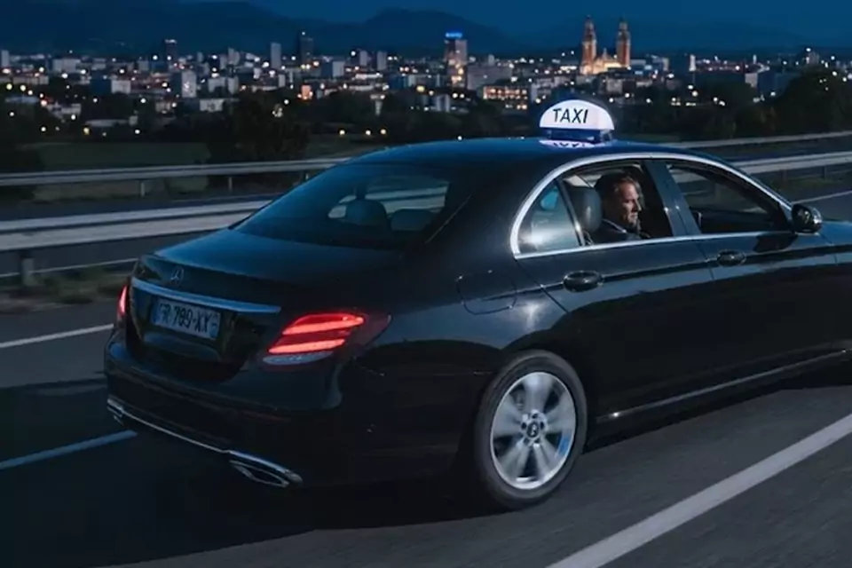Taxi Lille Sequedin : taxi noir en trajet de nuit avec la ville en arrière-plan