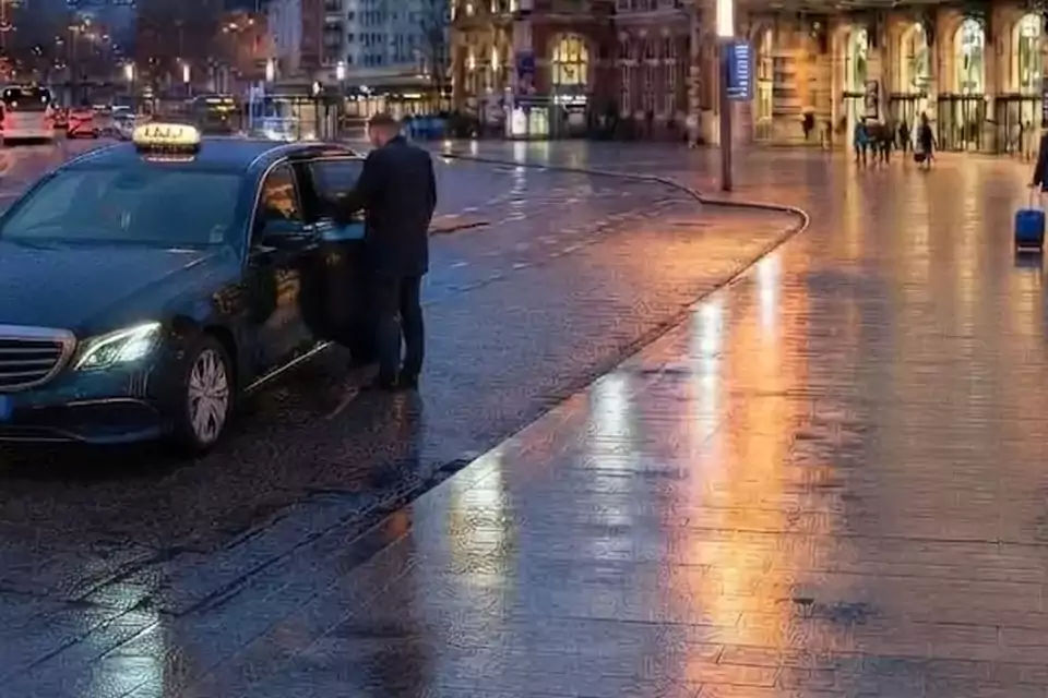 Taxi Lille Solesmes : chauffeur ouvrant la portière d’un taxi devant une gare