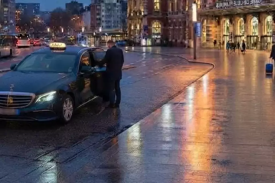 Taxi Lille Steenwerck : chauffeur ouvrant la portière d’un taxi devant une gare