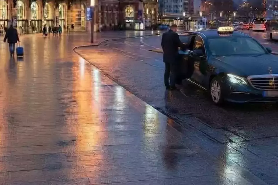 Taxi Lille Templemars : taxi noir stationné devant une gare en soirée