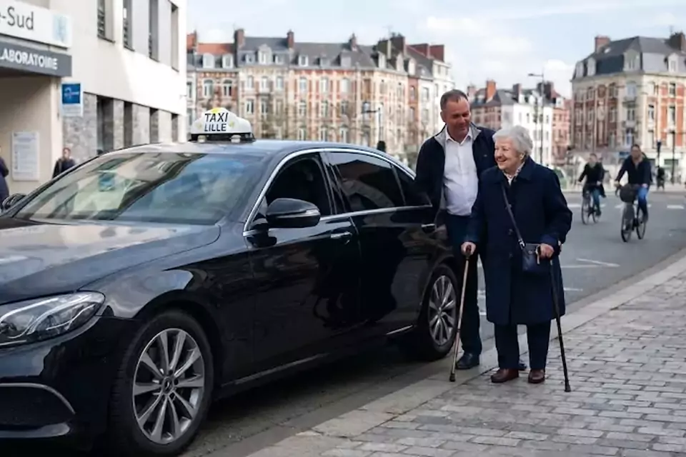 Taxi Lille Téteghem : chauffeur de taxi aidant une passagère devant un centre médical
