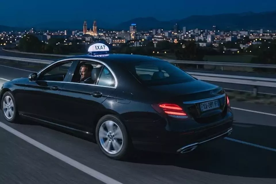 Taxi Lille Tournai : taxi noir en trajet de nuit avec la ville en arrière-plan
