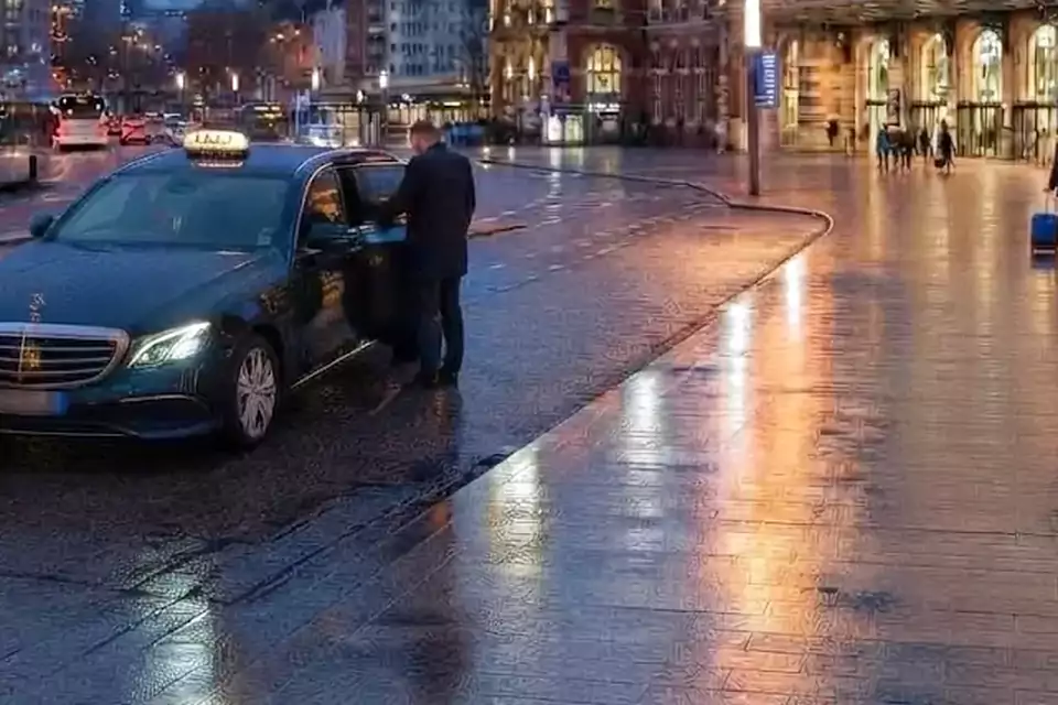 Taxi Lille Vitry-en-Artois : chauffeur ouvrant la portière d’un taxi devant une gare