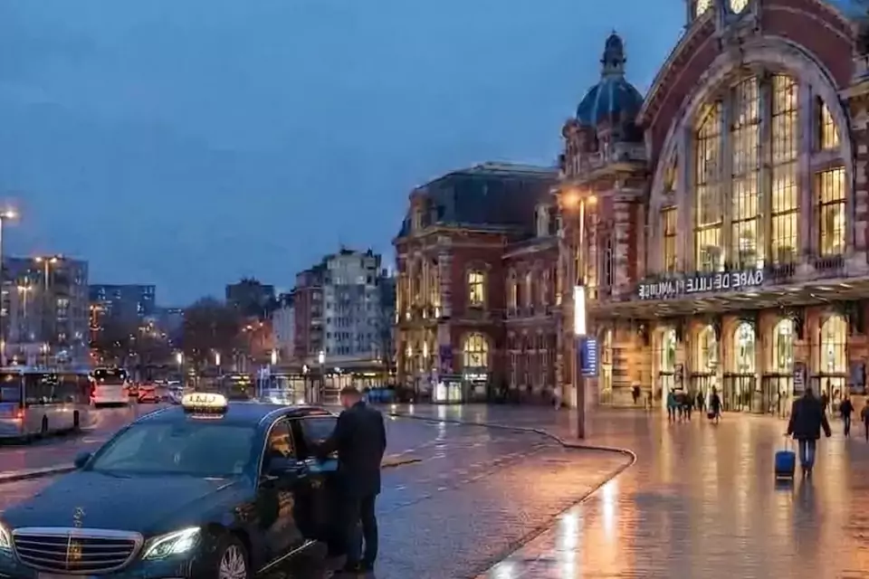 Taxi Lille Wallers : taxi noir stationné devant une gare en soirée