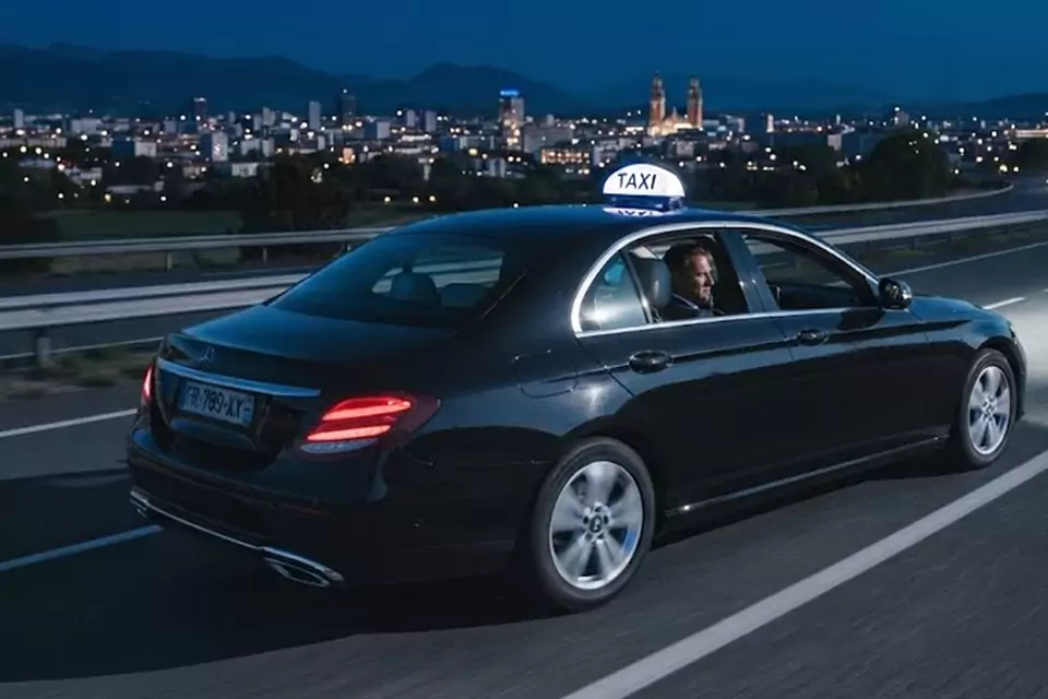 Taxi Lille Wervicq-Sud : taxi noir en trajet de nuit avec la ville en arrière-plan