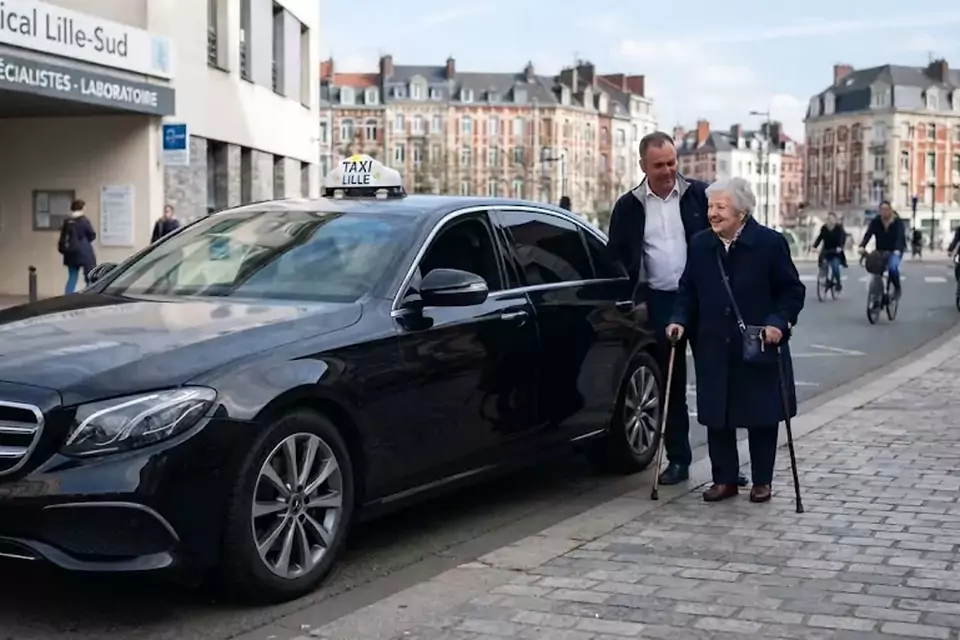 Taxi Lille Wimereux : chauffeur de taxi aidant une passagère devant un centre médical